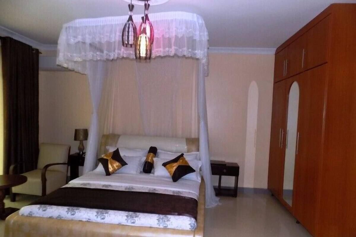 A hotel room with a bed, a nightstand, a wardrobe, and a chandelier.