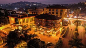 A multi-story hotel with a courtyard, balconies, and a well-lit entrance. - Nican Resort Hotel (Kampala)
