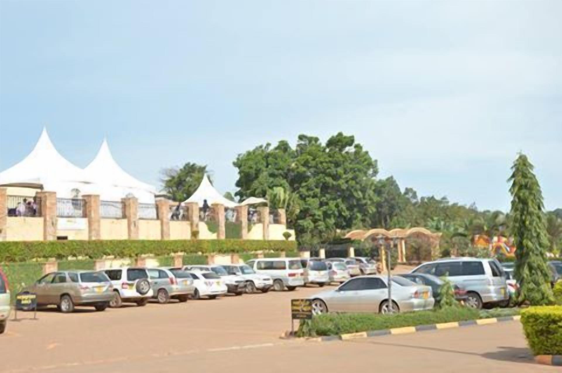 A parking lot with several cars and a building with white tents in the background.