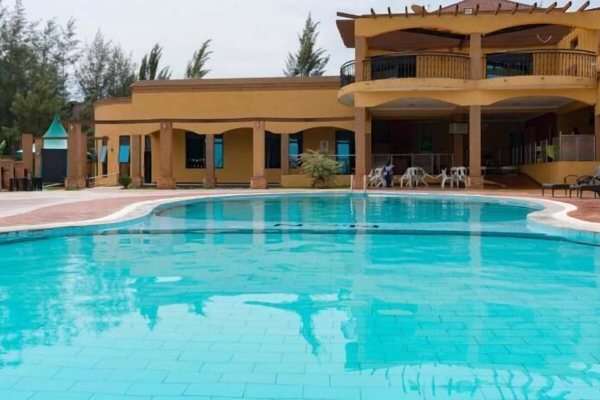 A swimming pool with a curved edge, surrounded by a paved area.