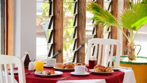 A breakfast table with plates of pastries, a glass of orange juice, and a cup of coffee. - Nican Resort Hotel (Kampala)