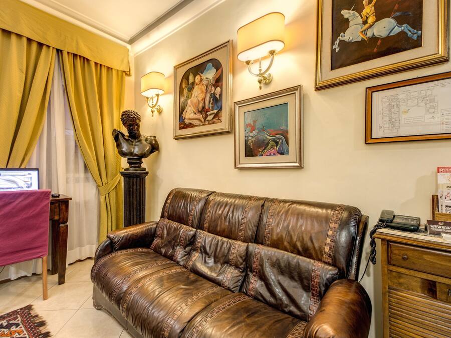 Uma sala de estar com um sofá de couro marrom, uma escrivaninha com um computador e uma luminária.