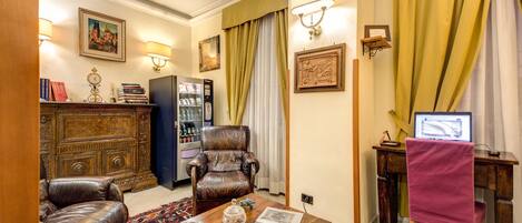 Una sala de estar tradicional con sillones de cuero, una mesa de centro de madera, una estantería, un escritorio con computadora y decoración en las paredes.