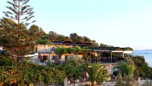 Une propriété située sur la côte, dotée d’une terrasse en pierre, d’un espace salon extérieur et offrant une vue sur la mer.