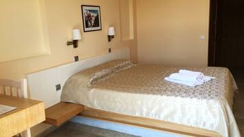 A hotel room with a bed, a desk, and a picture on the wall.