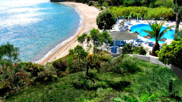 Une station balnéaire dotée d’une plage de sable, d’une piscine et d’une végétation luxuriante.