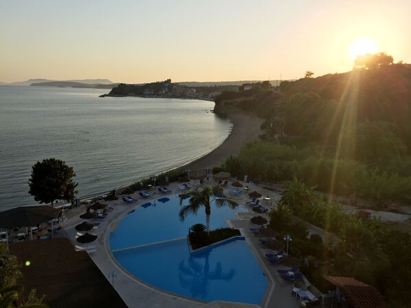 Un resort con piscina, tumbonas y vistas al mar al atardecer.