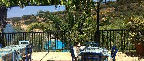 Une terrasse extérieure avec des tables et des chaises, une piscine et une vue sur un paysage côtier.