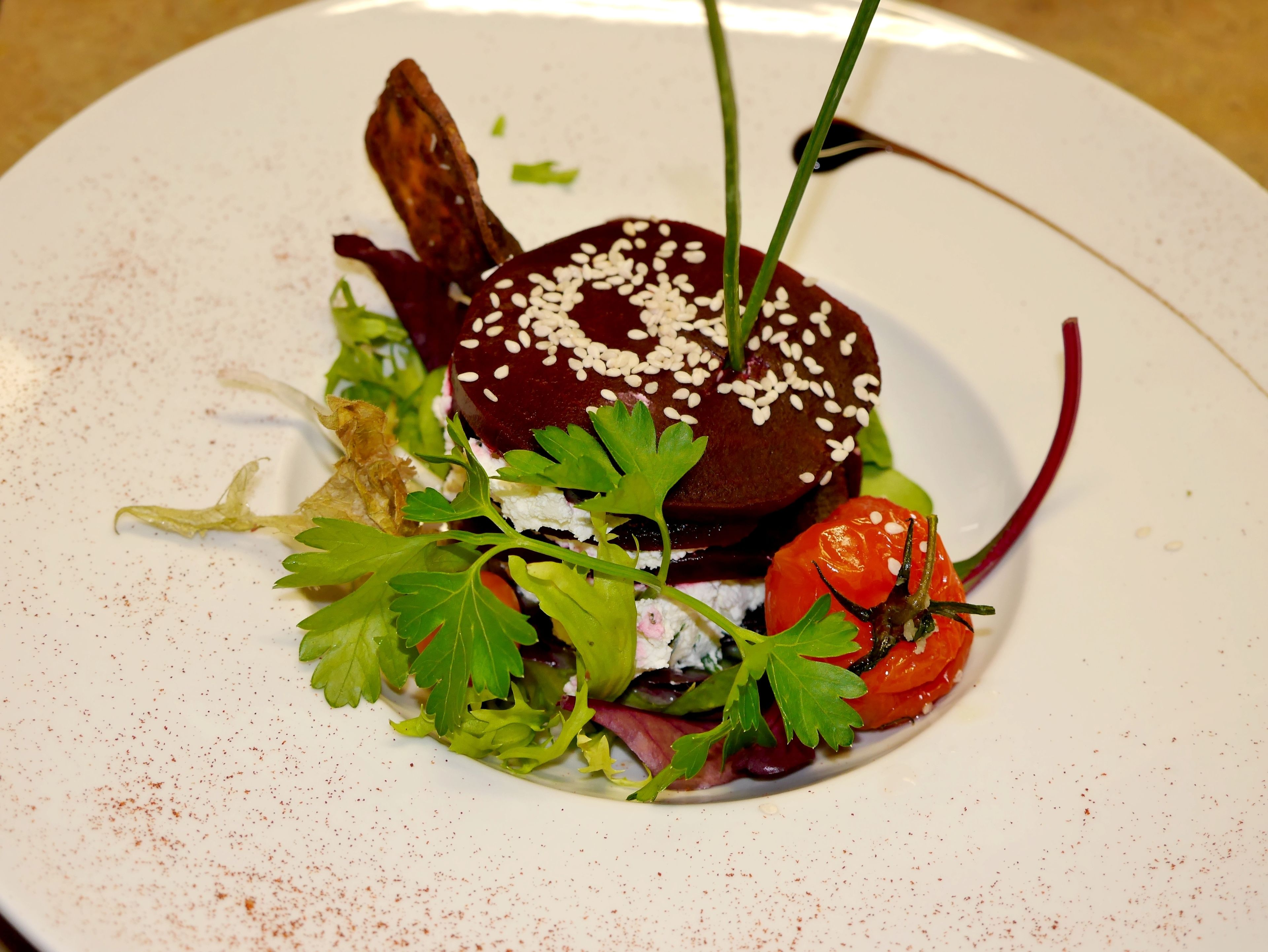 Une assiette contenant un plat à base de betteraves, des légumes verts et un poivron rouge.
