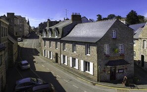A stone building with a row of windows, a sign for 'The Old Mill', and a street with parked cars.