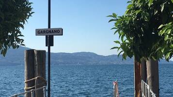 Ein Holzsteg mit einem Schild, auf dem 'GARGANO' steht, und Blick auf das Meer sowie ferne Berge.
