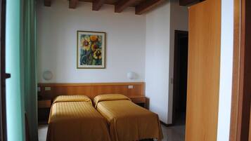 Ein Hotelzimmer mit zwei Betten, einem Holzkopfstück, einem Gemälde mit Sonnenblumen und einer Holztür.