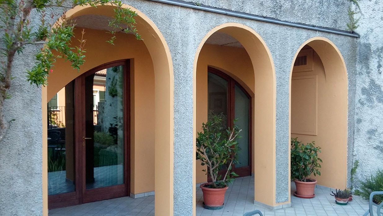 A building with three arched doorways, each with a potted plant.