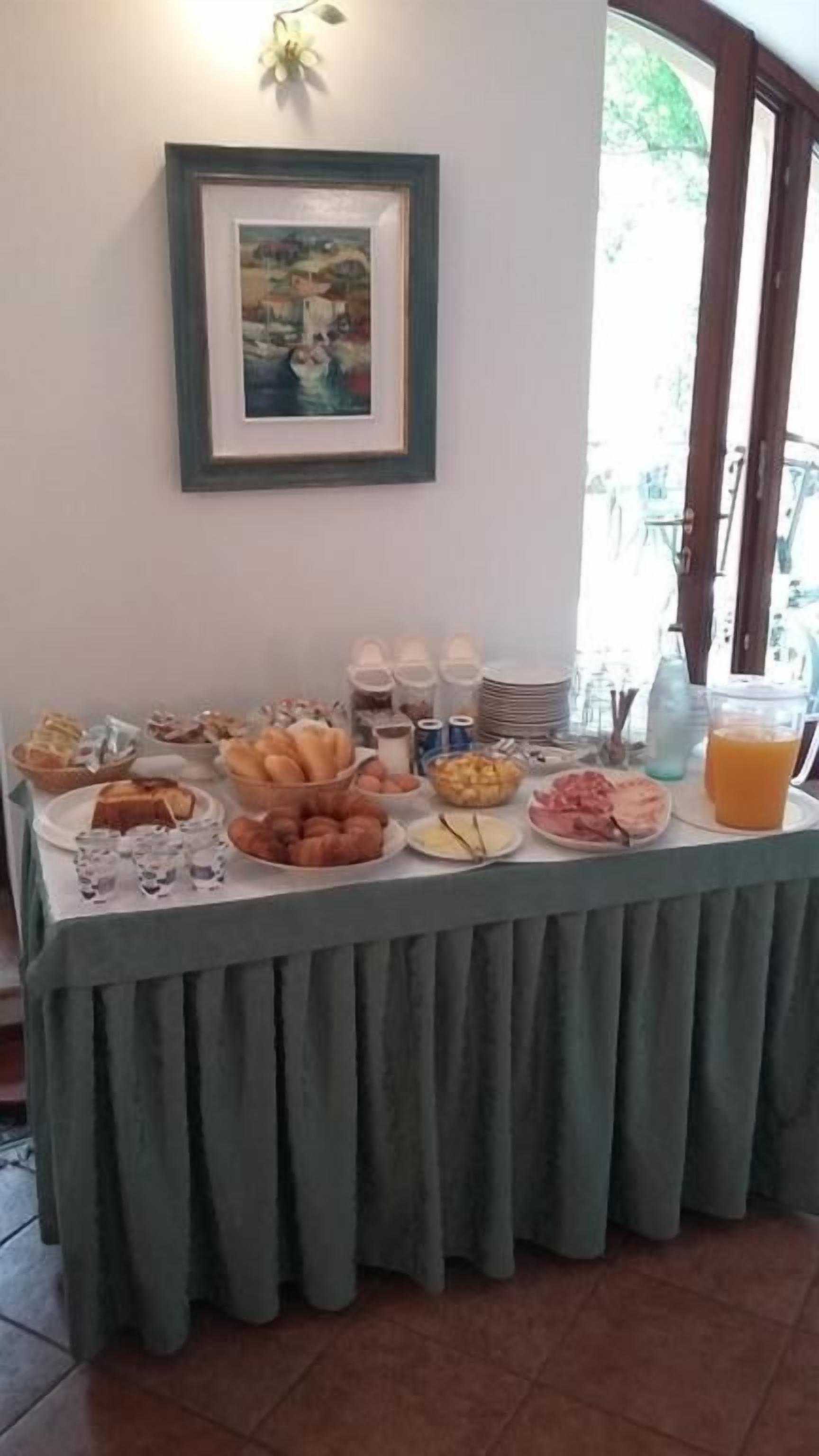Un buffet de petit-déjeuner proposant une variété d’aliments et de boissons, un tableau encadré au mur et une fenêtre donnant sur un paysage verdoyant.