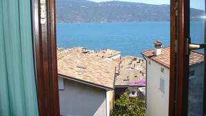 Une vue depuis une fenêtre donnant sur une ville côtière, avec ses bâtiments et une mer bleue et limpide.