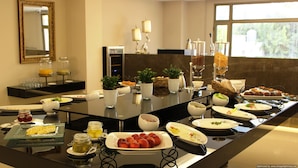 A buffet setup with various food items, including fruits, pastries, and beverages, arranged on a long table. - The Rooms Boutique Hotel (Jounieh)