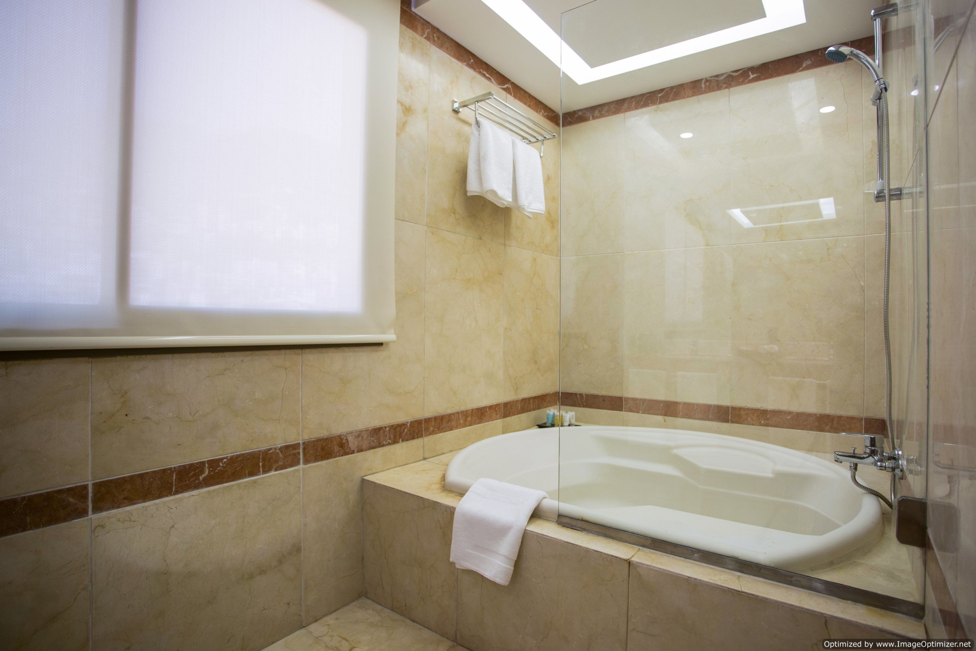 A modern bathroom with a glass-enclosed shower, a freestanding bathtub, and a towel rack.