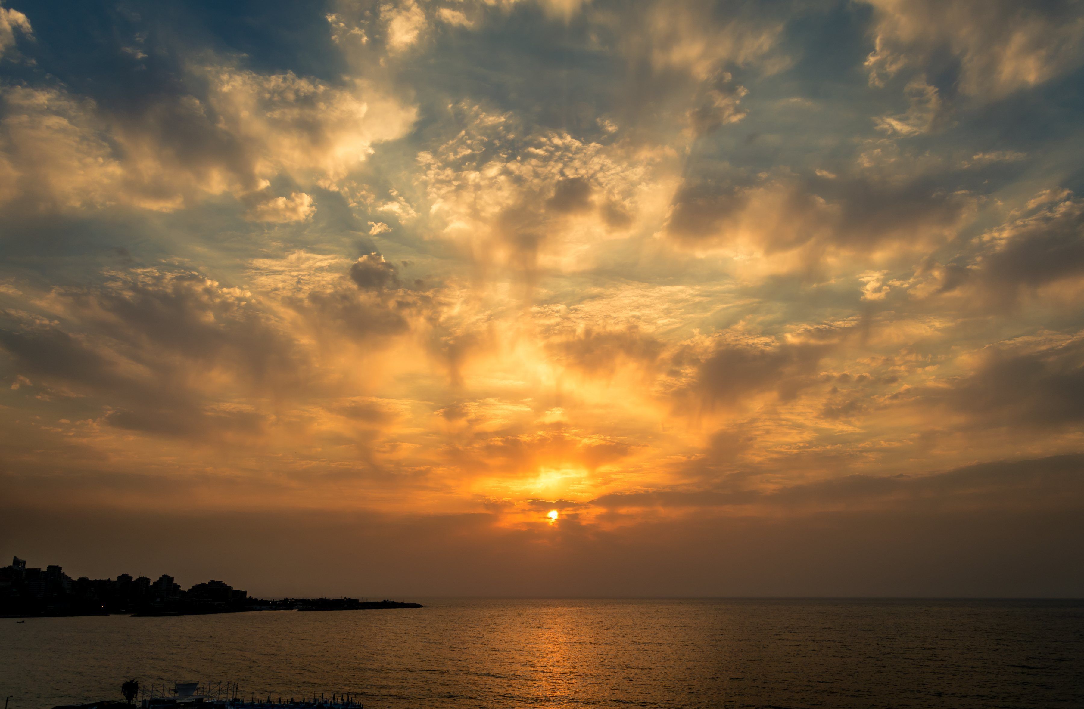 A sunset over a calm sea with a distant shoreline.
