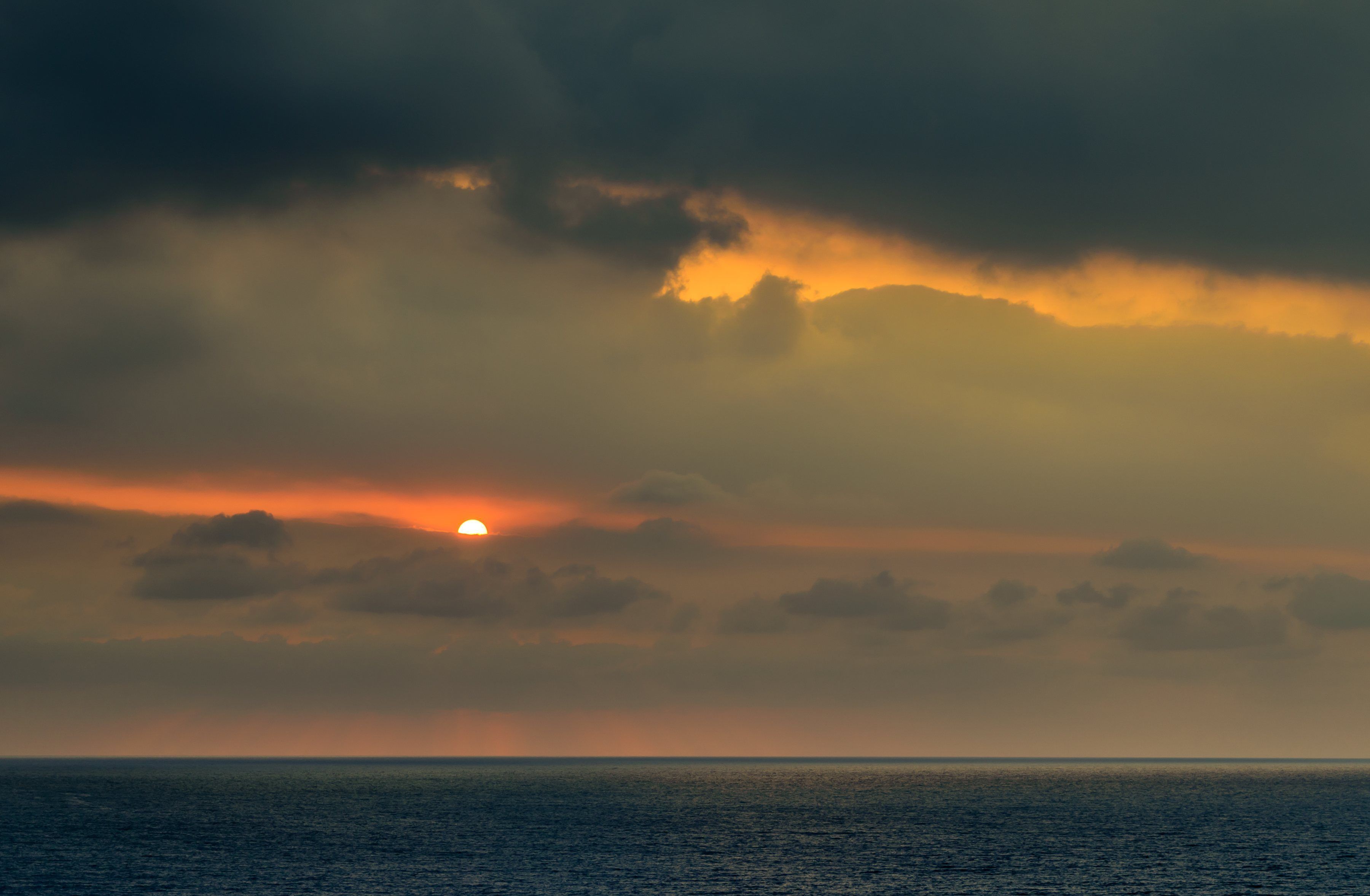 A sunset over the ocean with clouds.