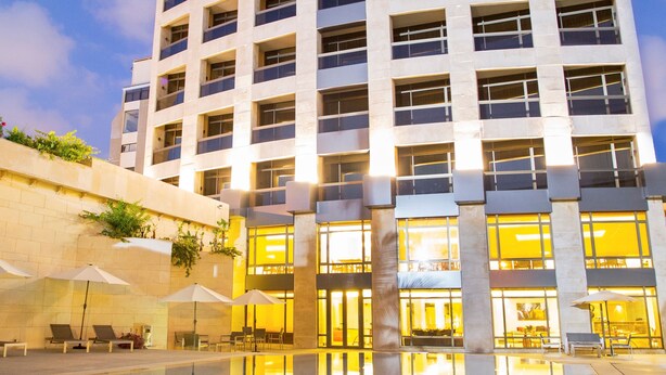 A high-rise building with multiple balconies and a reflective pool in the foreground. - The Rooms Boutique Hotel (Jounieh)