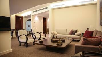 A modern living room with a sofa, armchairs, a coffee table, and a flat-screen TV.
