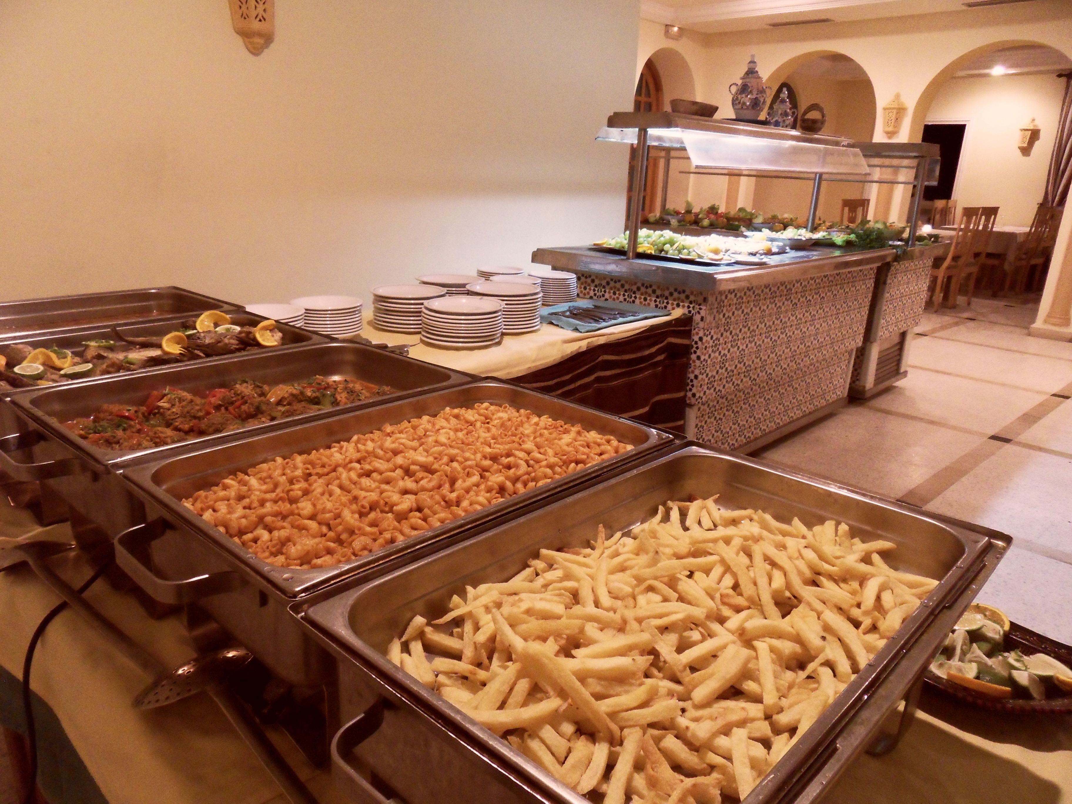 Un bufé con diversas opciones de comida, incluyendo pasta, papas fritas y ensaladas.