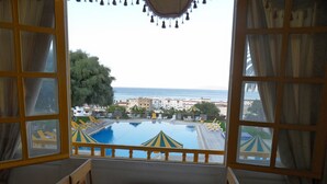 Un comedor con una mesa dispuesta para dos personas, con vistas a una piscina y al mar.