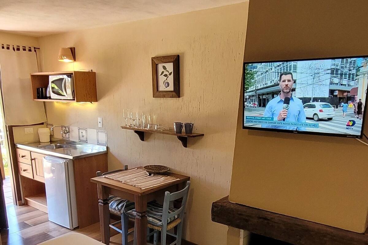 Hotellihuone, jossa on sänky, televisio, takka, keittotila ja ruokapöytä.