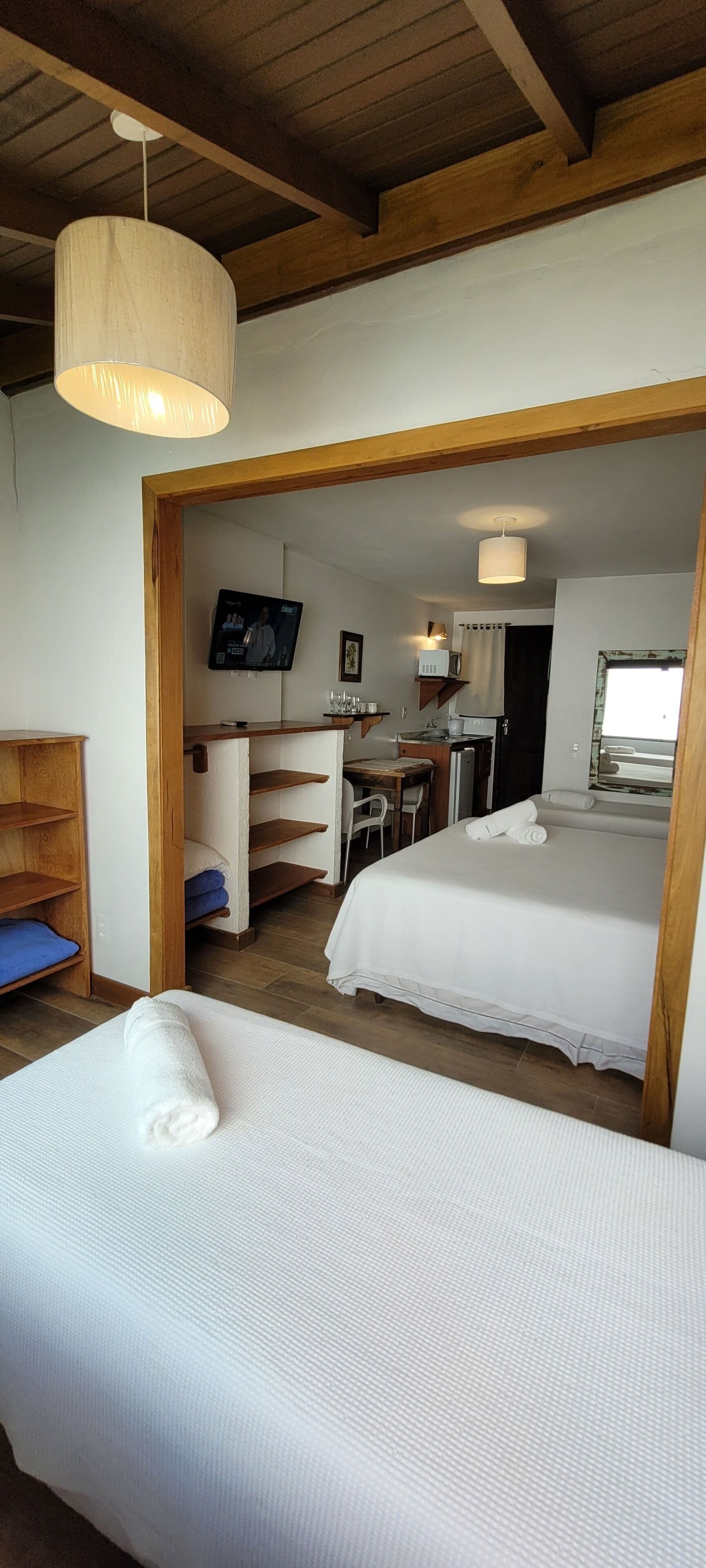 Habitación de hotel con dos camas, televisión, escritorio y kitchenette.
