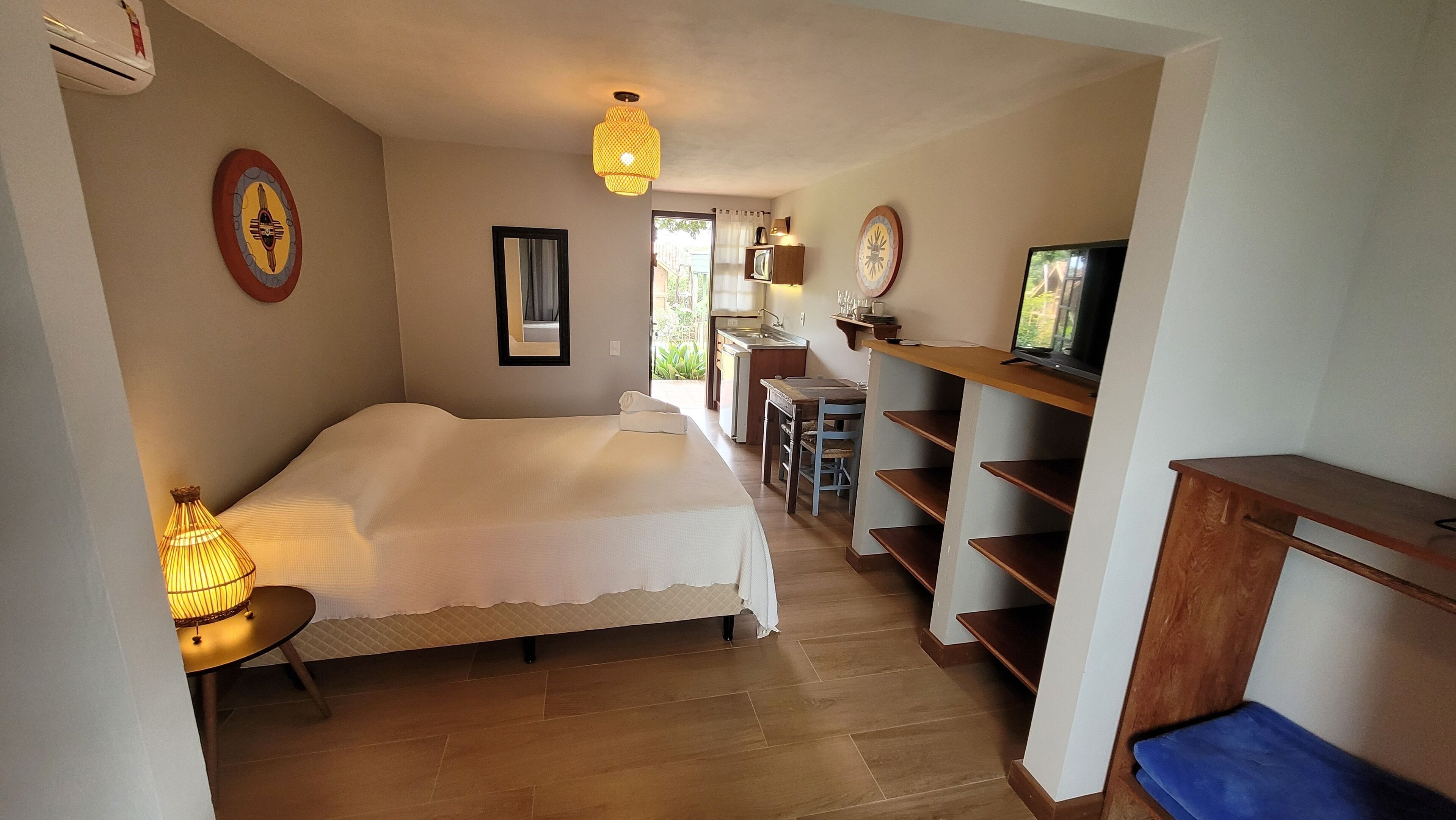 A compact room with a bed, a small kitchenette, a television, and a dining area.