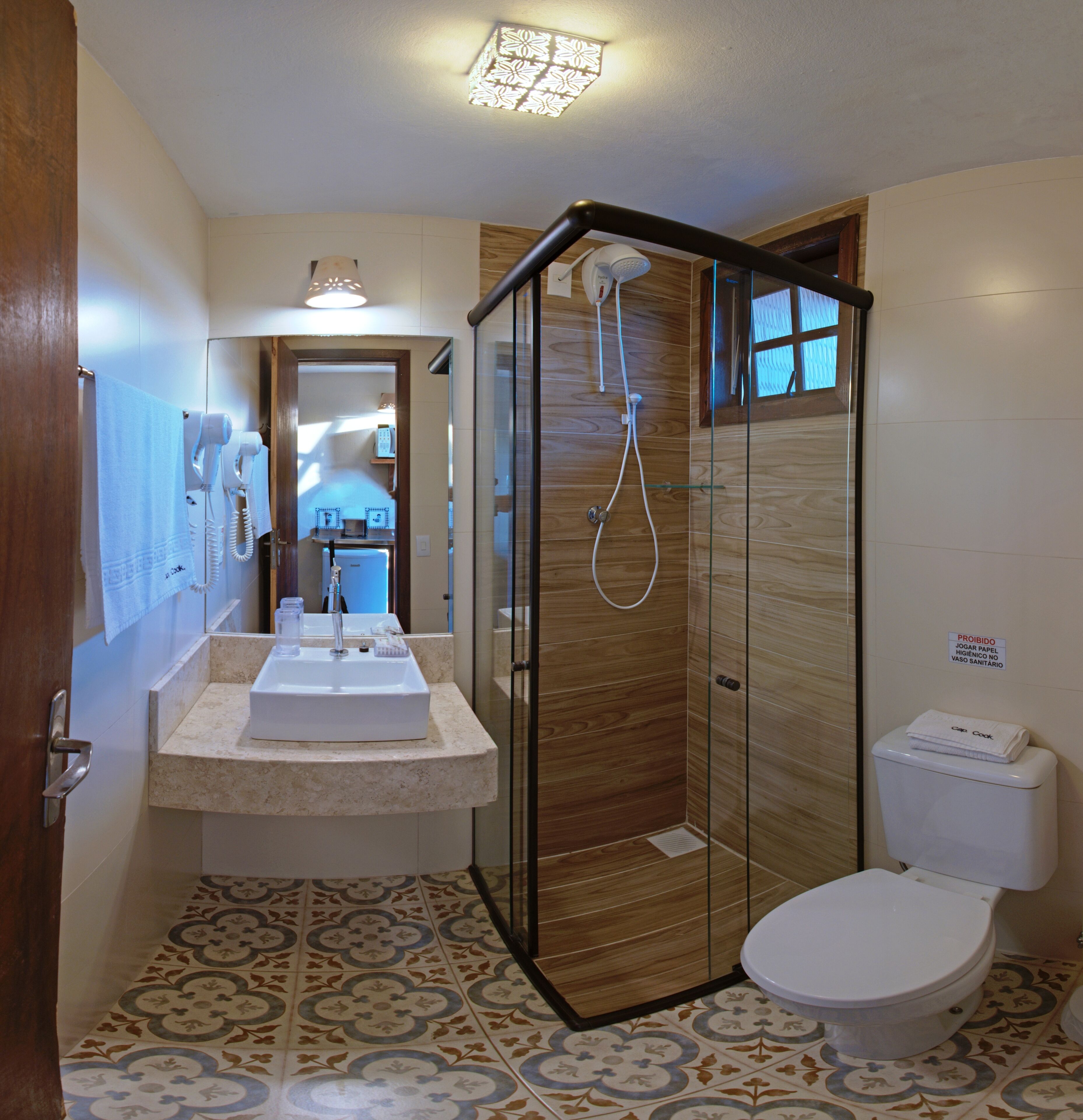 Un baño con cabina de ducha de vidrio, un lavamanos con espejo y un inodoro.
