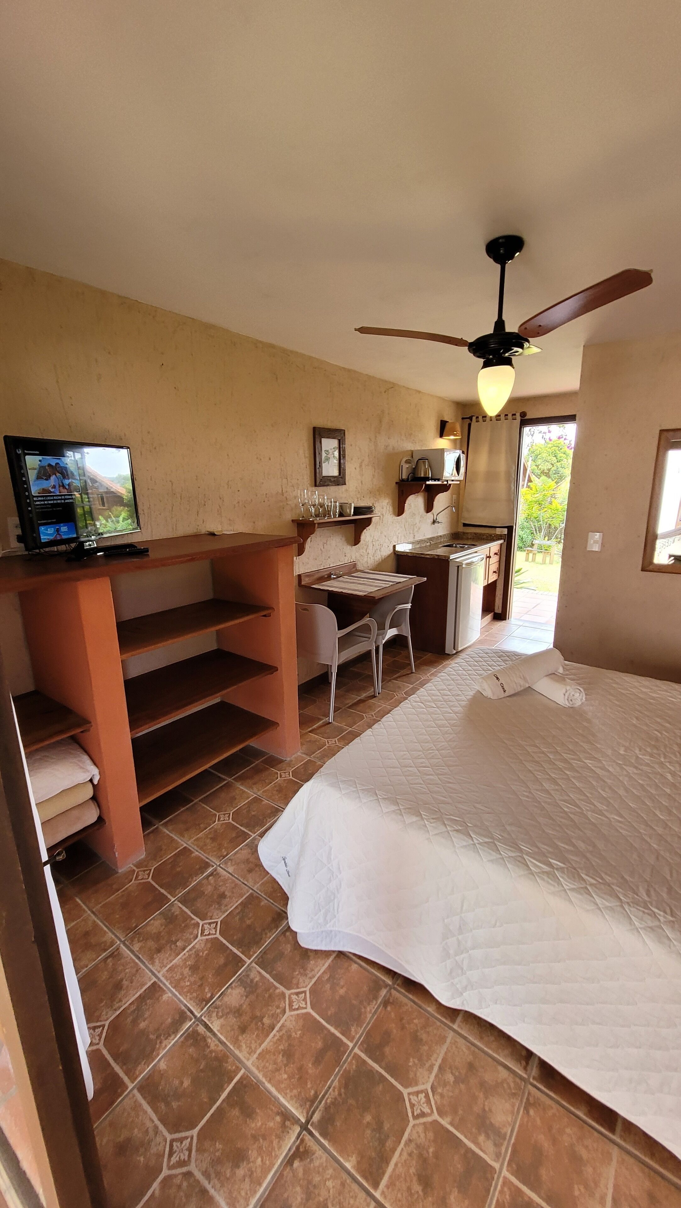 Una habitación con una cama, un escritorio, un televisor y un ventilador de techo.