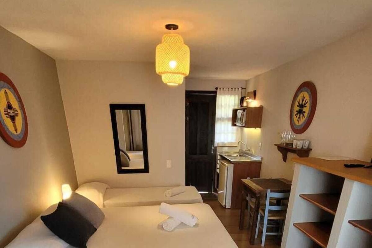Hotellihuone, jossa on kaksi sänkyä, työpöytä, tuoli ja pieni keittokomero.