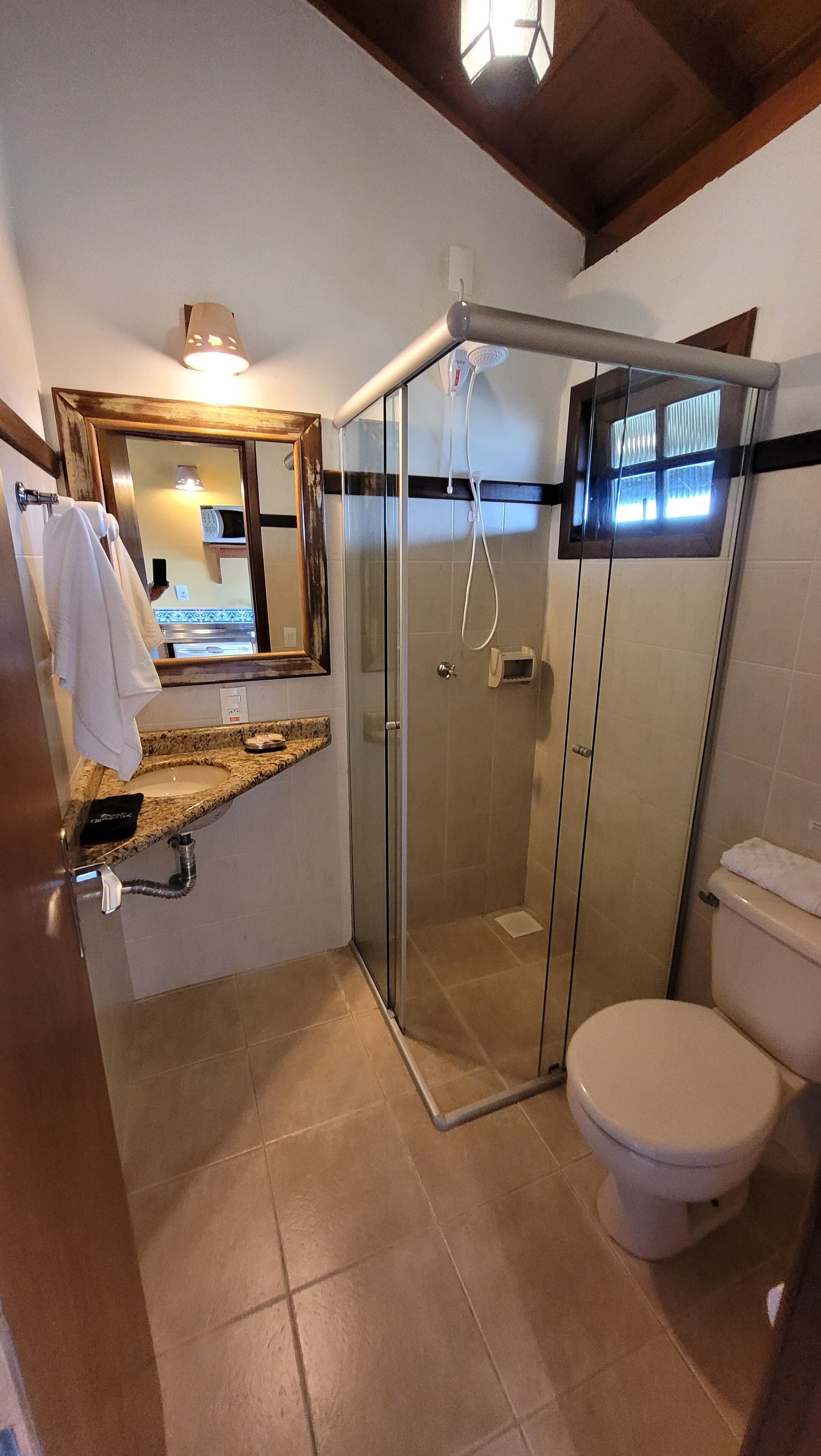 Un baño moderno con ducha de vidrio, inodoro blanco y encimera de granito con lavamanos.