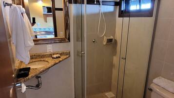 Un baño moderno con ducha de vidrio, inodoro blanco y encimera de granito con lavamanos.