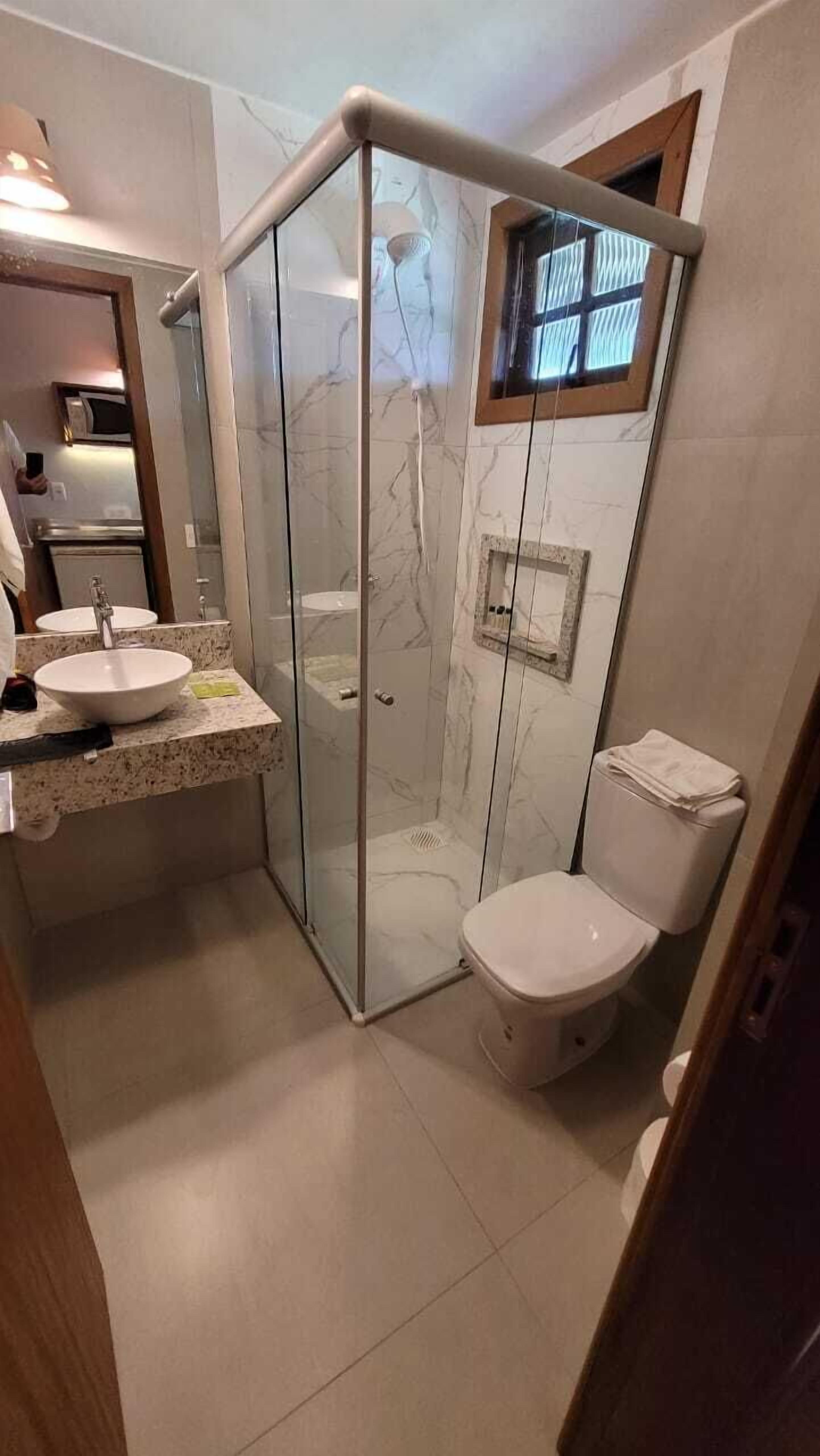 Un baño con ducha de vidrio, lavamanos e inodoro.