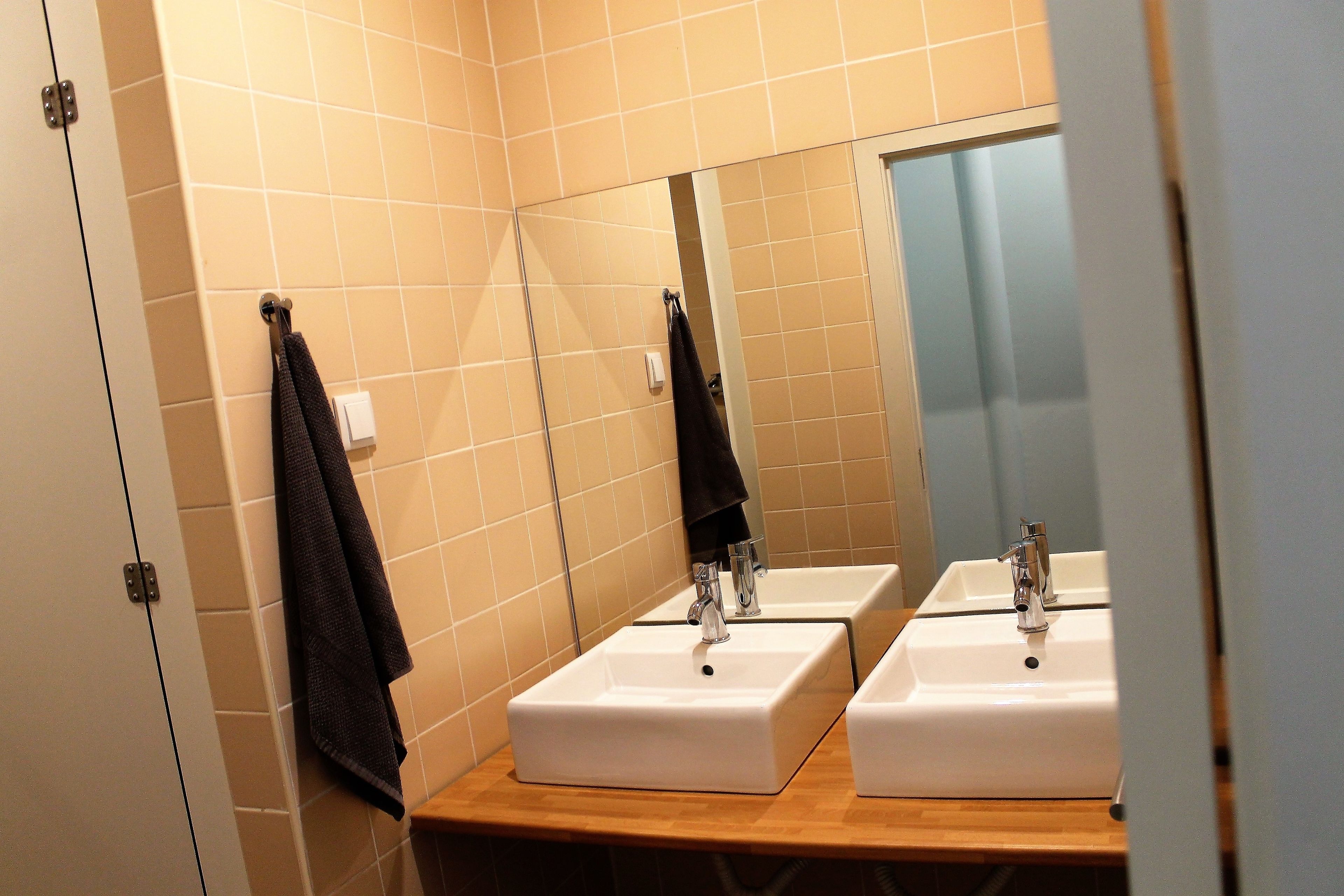 Un baño con dos lavamanos, un espejo y un perchero para toallas.