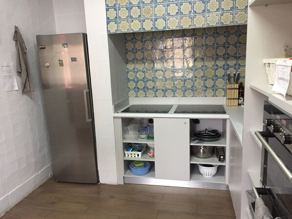 Una cocina compacta con refrigerador de acero inoxidable, un gabinete blanco con contenedores de almacenamiento y un salpicadero con diseño.