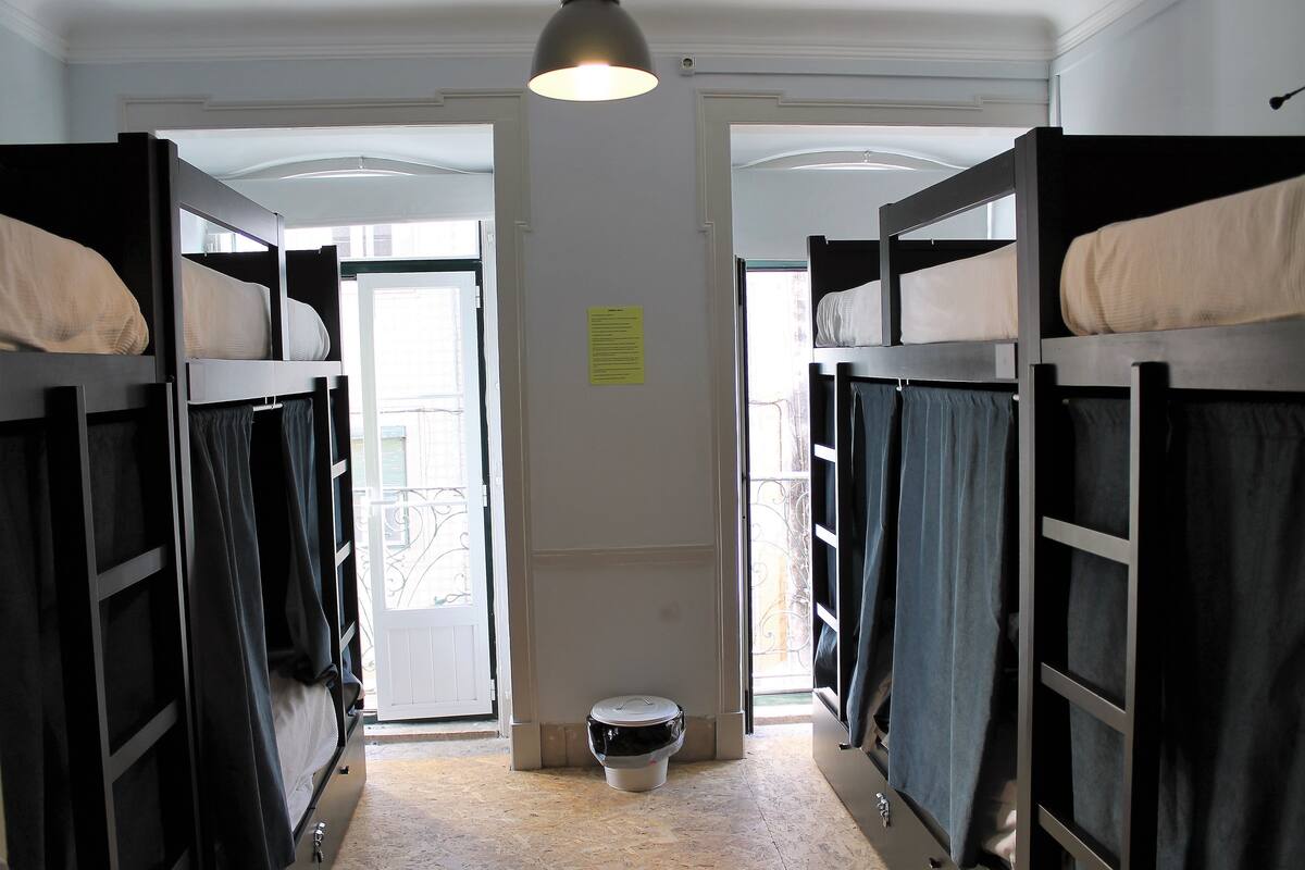 A dormitory room with bunk beds, a toilet, and a window.