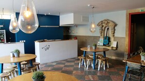 A modern cafe with a checkered floor, wooden tables, and hanging pendant lights. - Back To Lisbon Hostel (Lisbon)