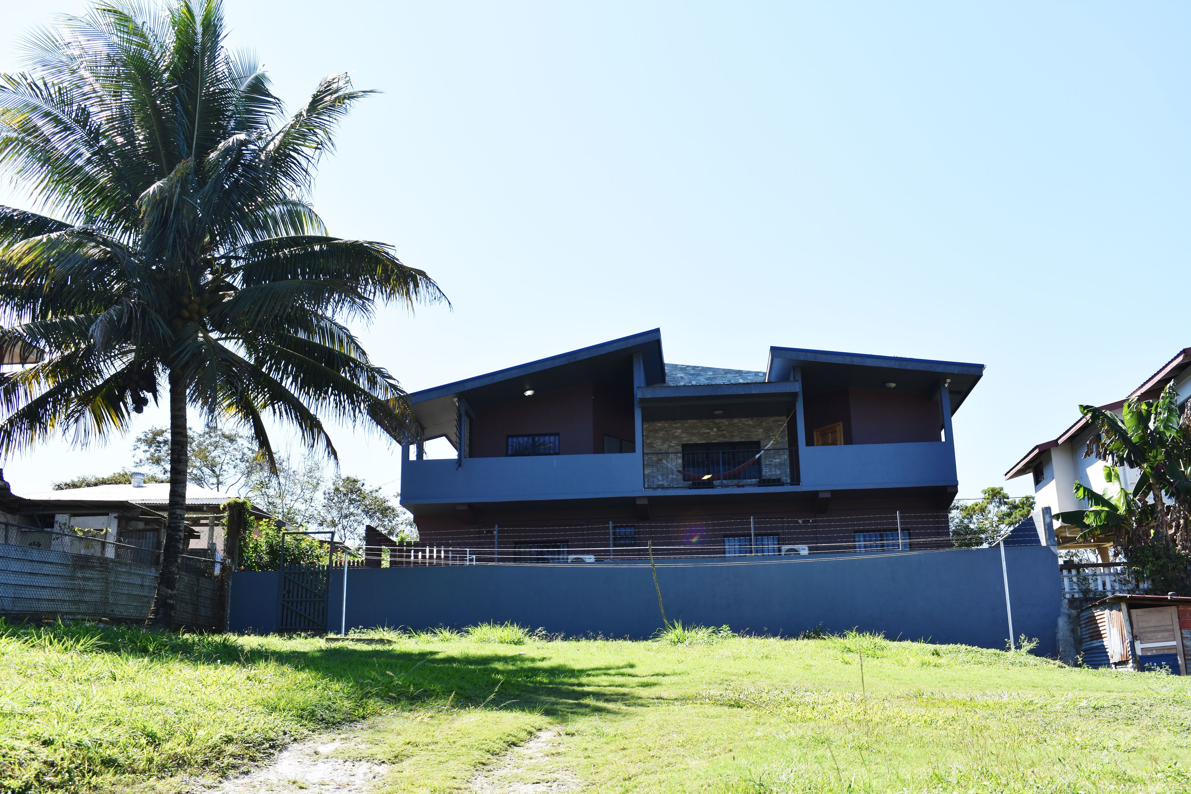 A modern two-story building with a flat roof and a balcony on the upper floor.