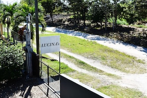 A sign reading "LUCINA'S" by a dirt road with a fence and greenery in the background.