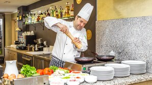 Een kok bereidt eten in een keuken, met verschillende ingrediënten en keukengerei.