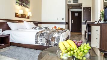 Una habitació d'hotel amb un llit, una taula de nit, una làmpada i un plat amb fruita sobre la taula.