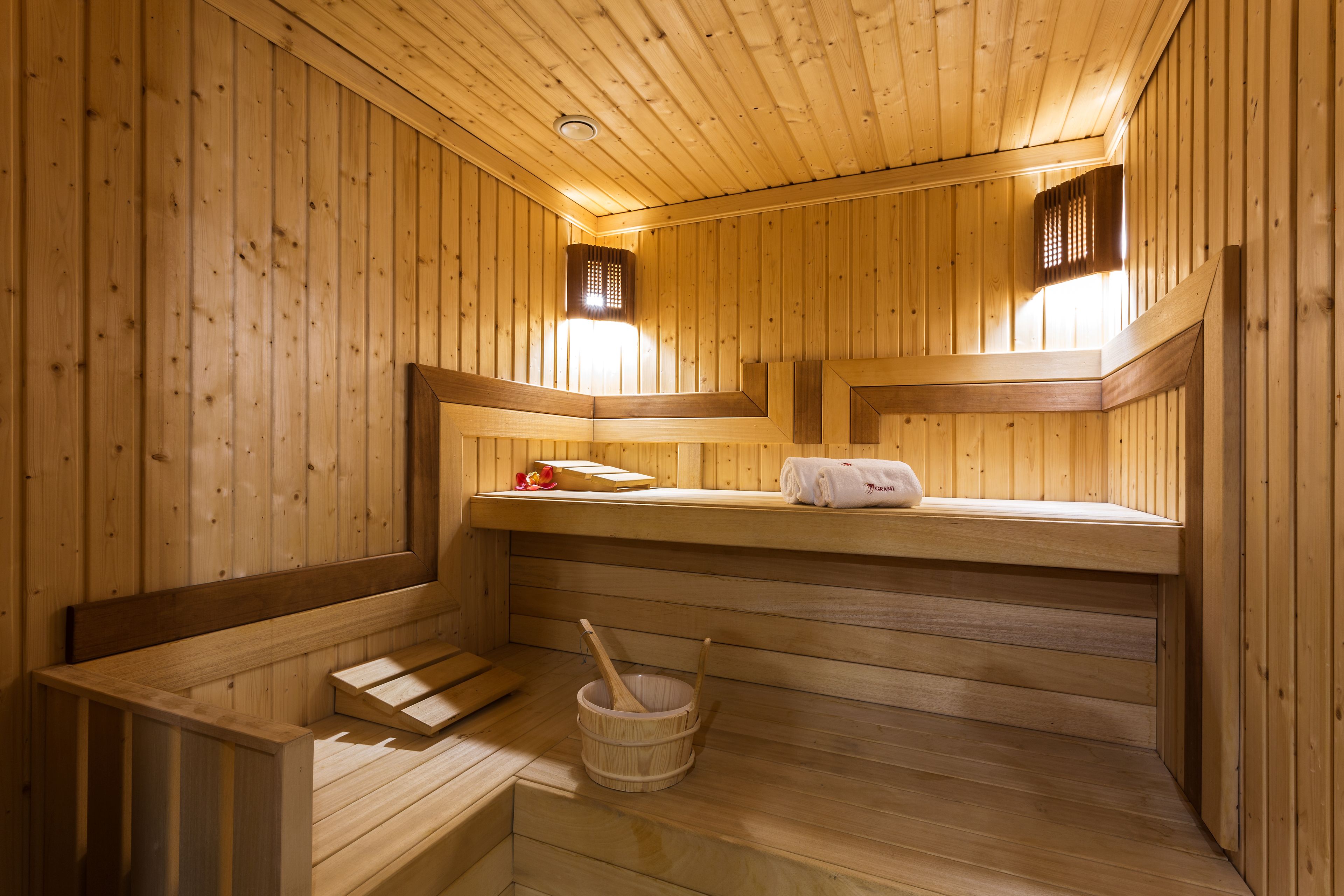 Una sauna de madera con bancos, un perchero para toallas y un cubo de madera.