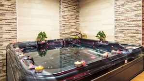 Een moderne spa met een ruime hottub, kaarsen en decoratieve planten.