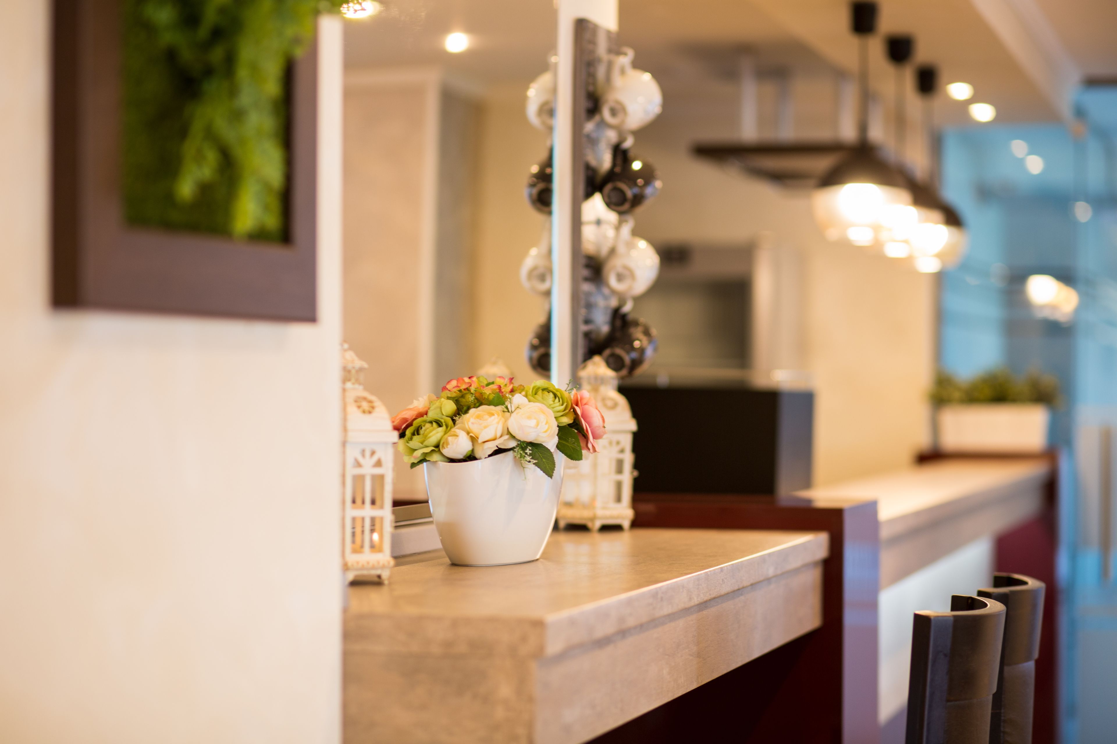A well-lit reception area with a marble counter, a white vase with flowers, and decorative lanterns.