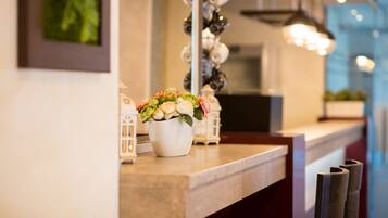 A well-lit reception area with a marble counter, a white vase with flowers, and decorative lanterns.