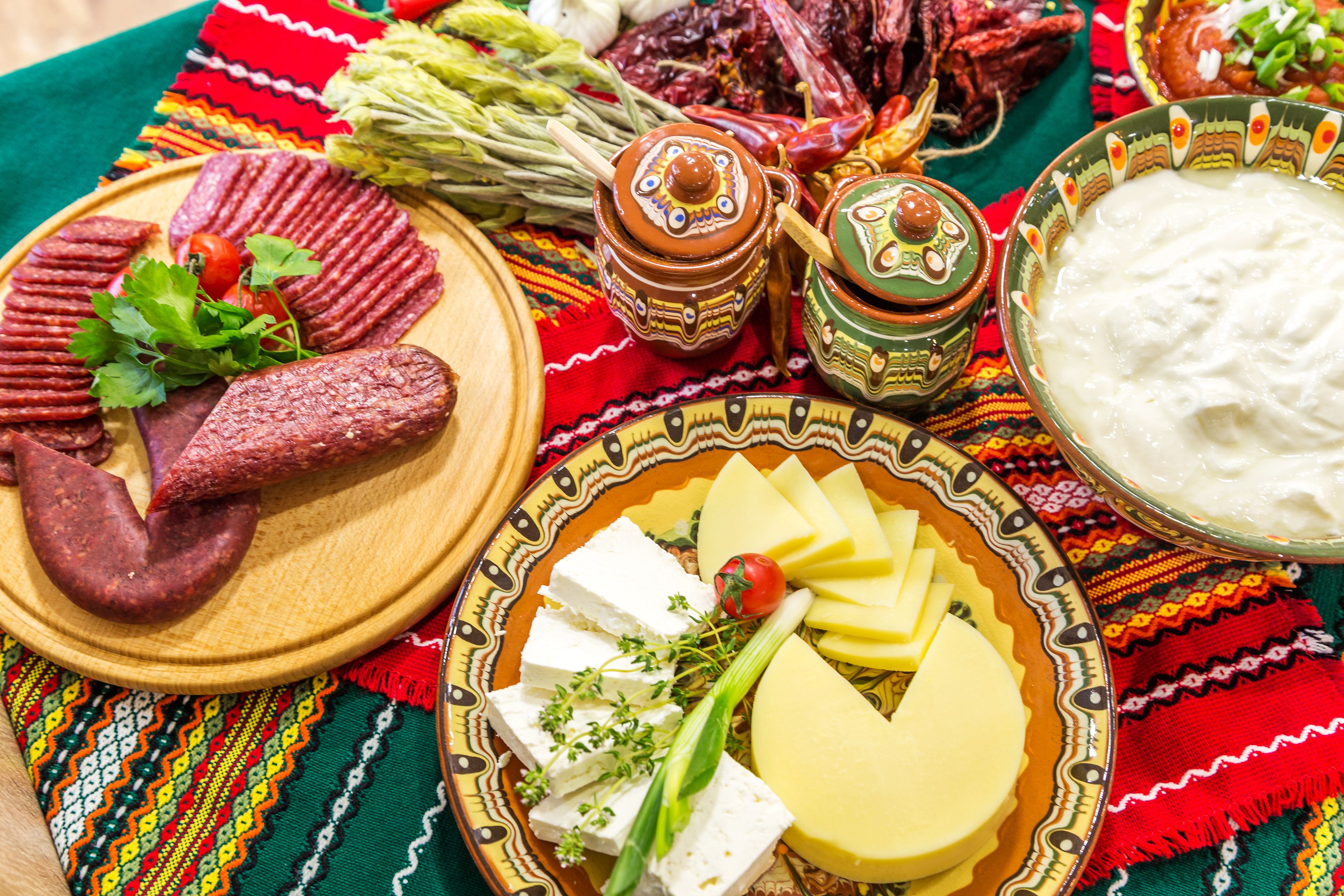 A table with various food items including sausages, cheese, and a bowl of yogurt.