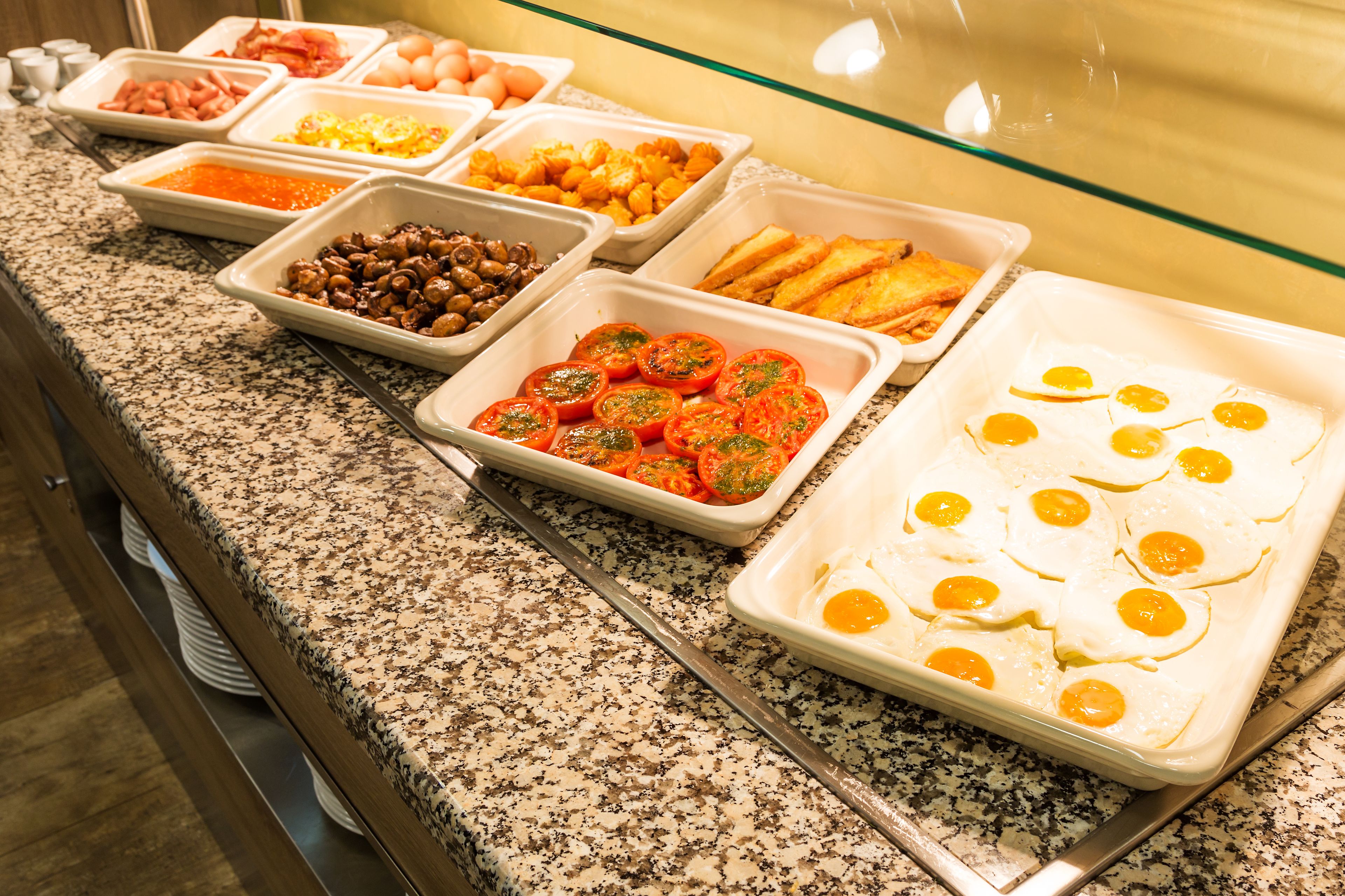 A buffet with various food options including eggs, tomatoes, and beans.